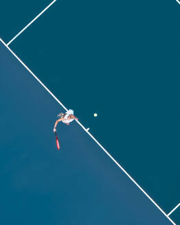 Aerial drone view of a female tennis player laying on a blue tennis court in Melbourne, Victoria, Australia. - AAEF26263