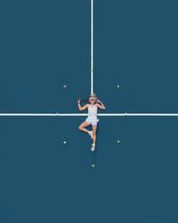 Aerial drone view of a female tennis player laying on a blue tennis court in Melbourne, Victoria, Australia. - AAEF26264