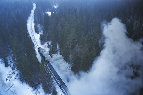 Aerial view of a train across the forest with snow in winter, Ruskeala, Republic of Karelia, Russia. - AAEF26353