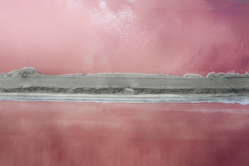 Aerial view of a salt lake with bright pink water and a sand barrier running down the middle of the lake, Walvis Bay, Erongo, Namibia. - AAEF26492