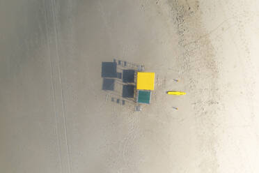 Luftaufnahme eines gelben Rettungsschwimmerstuhls und eines Rettungsbretts an einem Strand bei Sonnenaufgang mit langen Schatten, die von den Stühlen geworfen werden, Durban, Kwa Zulu Natal, Südafrika. - AAEF26493