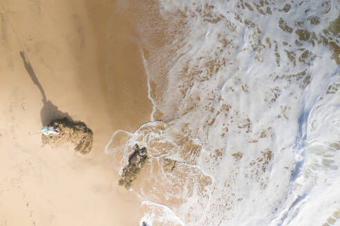 Luftaufnahme eines Mannes, der auf einem Felsen steht und vom Strand aus im Meer fischt, Wilderness, Westkap, Südafrika. - AAEF26502