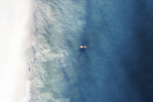 Aerial view of an orange paddle board in the crystal clear ocean water with small waves lapping onto the beach, Cape Town, Western Cape, South Africa. - AAEF26516