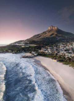Aerial view of Lions Head Mountain at sunset with a pink horizon, white sandy beach, and blue waves rolling onto shore, Cape Town, Western Cape, South Africa. - AAEF26528
