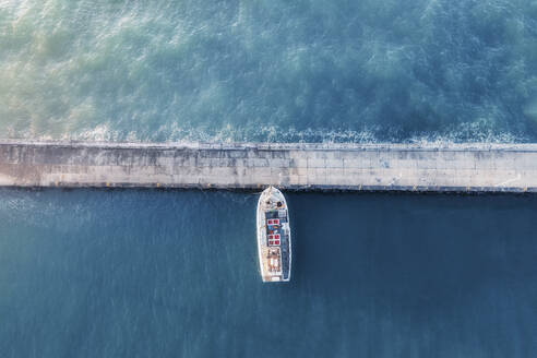 Luftaufnahme eines Fischerboots, das in einem Hafen angedockt ist, mit blauem Wasser, das ein minimalistisches Bild erzeugt, Kapstadt, Westkap, Südafrika. - AAEF26535