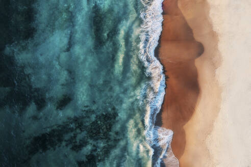 Aerial view of a white sandy beach with white waves rolling onto shore and crystal clear blue water, Port Noarlunga, South Australia, Australia. - AAEF26545