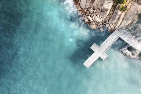 Luftaufnahme eines kreuzförmigen Stegs über blauem Wasser mit Granitfelsen und Felsbrocken im Bild, Port Elliot, South Australia, Australien. - AAEF26551
