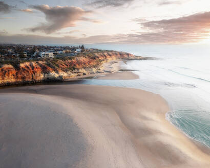 Luftaufnahme von Southport Beach und Klippen bei Sonnenuntergang, mit rosa Wolken und einem bunten Regenschirm am Strand von Onkaparinga, South Australia, Australien. - AAEF26552