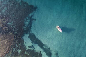 Luftaufnahme eines kleinen Fischerboots in blauem tropischem Wasser mit einem im Wasser sichtbaren Riff, Port Willunga, South Australia, Australien. - AAEF26557