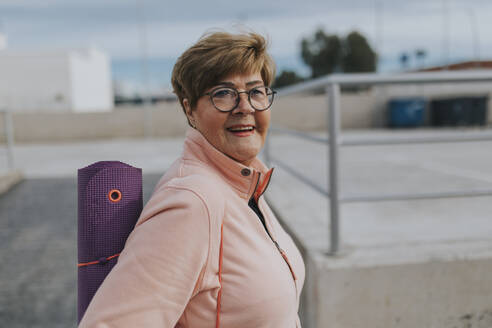 Smiling senior woman with exercise mat - DMGF01258