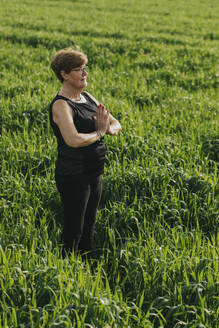 Aktive ältere Frau übt Yoga auf einer Wiese - DMGF01270