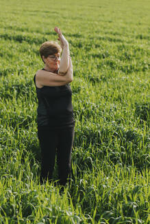 Fit retired senior woman practicing yoga in meadow - DMGF01272