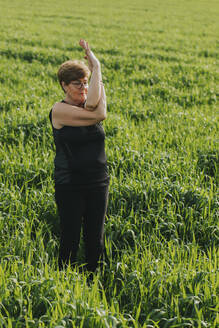 Fitte Seniorin im Ruhestand, die auf einer Wiese Yoga praktiziert - DMGF01272