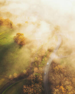 Luftaufnahme einer Straße in Ascain bei Sonnenaufgang mit Nebel, Französisches Baskenland, Pyrénées-Atlantiques, Nouvelle-Aquitaine, Frankreich. - AAEF26748