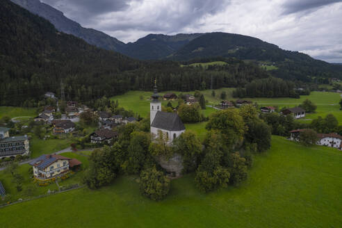 Aerial drone view of Wallfahrtskirche St. Nikolaus with Golling an der Salzach in background at cloudy day, Golling an der Salzach, Salzburg, Austria. - AAEF26786