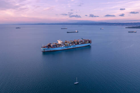 Aerial Drohne Blick auf Segelyacht Kreuzfahrt auf adriatischen Meer mit großen Containerschiff im Hintergrund, Adria, Izola, Slowenien. - AAEF26817