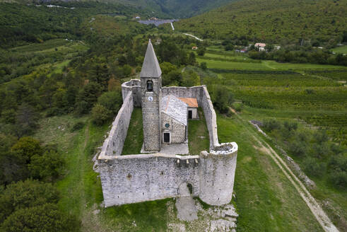 Drohnenaufnahme der Kirche der Heiligen Dreifaltigkeit (Cerkev Sv. Trojice), umgeben von einer Mauer, Hrastovlje, Koper, Slowenien. - AAEF26819