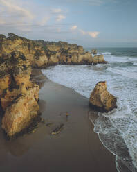 Luftaufnahme eines Spaziergängers am Strand von Praia dos Tres Irmaos mit Sandsteinklippen und nautischer Landschaft, Algarve, Portugal. - AAEF26845