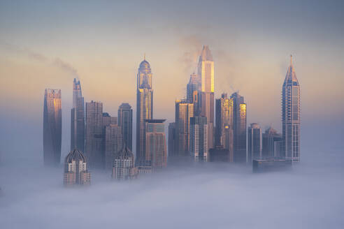 Aerial view of Dubai Marina with Cayan Tower emerging from the mist, Dubai, United Arab Emirates. - AAEF27022