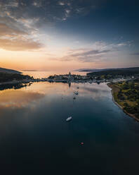 Aerial view of a serene coastal town with beautiful orange sunset over the calm ocean, Osor, Primorje-Gorski Kotar, Croatia. - AAEF27094