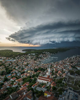 Aerial view of a menacing Supercell storm over a coastal town with red roofs and a church steeple, Mali Losinj, Primorje-Gorski Kotar, Croatia. - AAEF27151