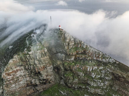 Luftaufnahme des alten Cape Point-Leuchtturms im Cape Point Nature Reserve Park mit tief hängenden Wolken auf dem Bergkamm, Kapstadt, Westkap, Südafrika. - AAEF27313