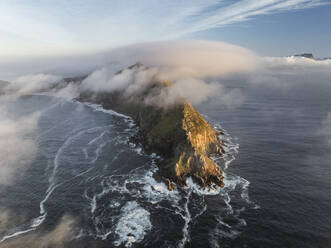 Aerial view of the Old Cape Point Lighthouse in Cape Point Nature Reserve park with low clouds on the mountains ridge, Cape of Good Hope, Cape Town, Western Cape, South Africa. - AAEF27316