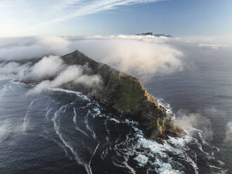 Aerial view of the Old Cape Point Lighthouse in Cape Point Nature Reserve park with low clouds on the mountains ridge, Cape of Good Hope, Cape Town, Western Cape, South Africa. - AAEF27318