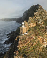 Luftaufnahme des alten Cape Point-Leuchtturms im Cape Point Nature Reserve Park mit tief hängenden Wolken auf dem Bergkamm, Kap der Guten Hoffnung, Kapstadt, Westkap, Südafrika. - AAEF27321