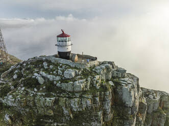 Aerial view of the Old Cape Point Lighthouse in Cape Point Nature Reserve park with low clouds, Cape Town, Western Cape, South Africa. - AAEF27324