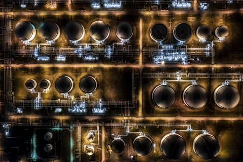Luftaufnahme eines beleuchteten Chemiewerks mit Metallzylindern und futuristischem Glanz, Leuna, Sachsen-Anhalt, Deutschland. - AAEF27481