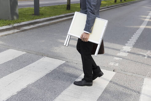 Low section of real estate agent carrying placard while crossing street - MASF43568