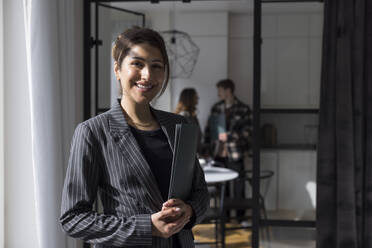 Portrait of confident female real estate agent holding folder at home - MASF43600