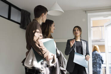 Low angle view of female real estate agent assisting clients during house visit - MASF43617
