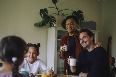 Happy gay couple talking with daughters while having breakfast at home - MASF43632