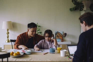 Gay father assisting daughter while doing homework at home - MASF43634