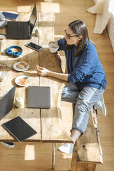 IT-Techniker sitzt mit Tee und Keksen am Tisch im Büro eines Start-ups - EVKF00112