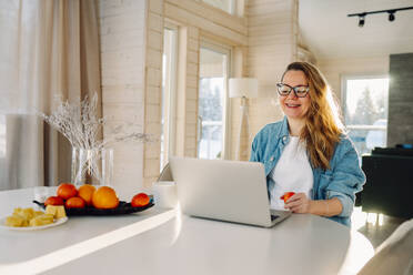 Smiling freelancer having video call using laptop at home office - OLRF00219