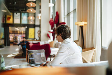 Geschäftsfrau mit Laptop in der Lobby eines Hotels - MDOF01881