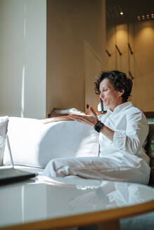 Selbstbewusste Geschäftsfrau bei einem Videogespräch über einen Laptop in der Lobby eines Hotels - MDOF01890