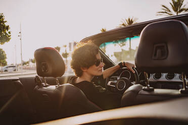 Woman wearing sunglasses driving convertible car on sunny day - MDOF01932