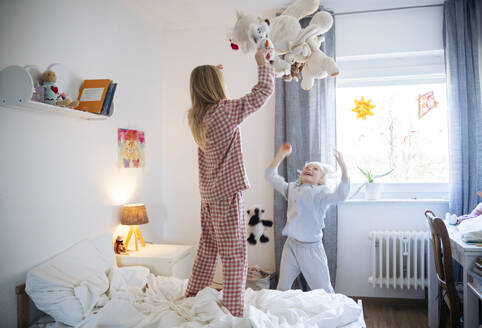 Verspielte Geschwister werfen Teddybär im Schlafzimmer zu Hause - NJAF00858