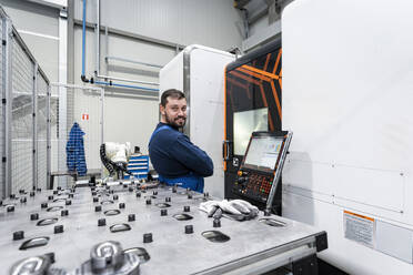 Lächelnder Wartungsingenieur bei der Arbeit in einer modernen Fabrik - AAZF01681