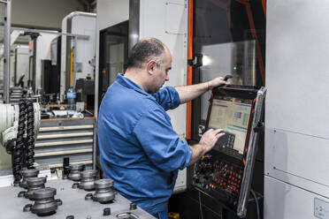 Maintenance engineer operating modern machinery in factory - AAZF01685