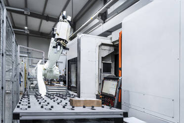 White robotic arm with CNC machinery in factory - AAZF01688