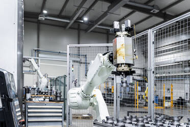 White robotic arm with machinery in modern manufacturing building - AAZF01694