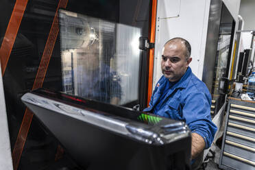Wartungsingenieur, der CNC-Roboter in einer Produktionsstätte bedient - AAZF01700