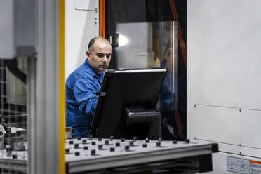 Wartungsingenieur, der eine CNC-Maschine in einer modernen Fabrik bedient - AAZF01721