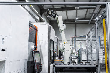 Weißer Roboterarm mit CNC-Maschinen in einer modernen Produktionsstätte - AAZF01725