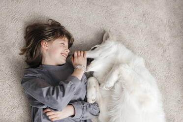 Glückliches Mädchen spielt mit Hund auf Teppich zu Hause - ELMF00101